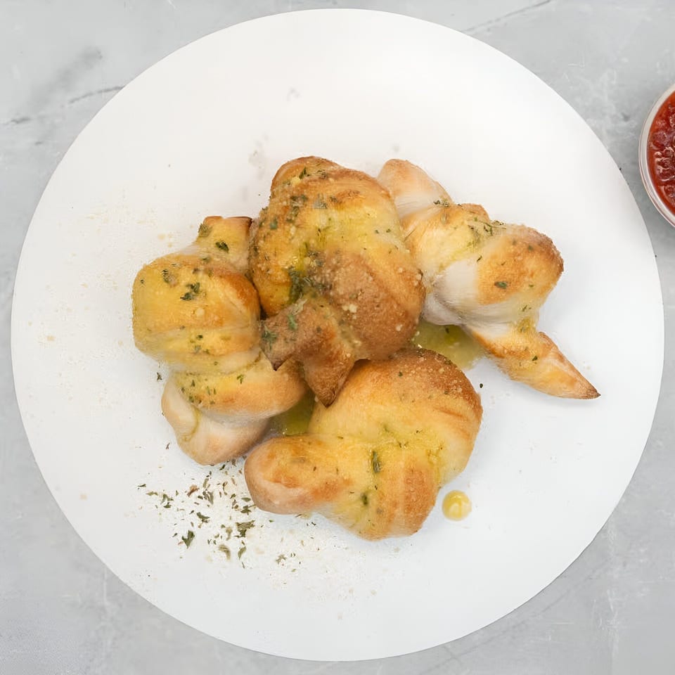 Garlic knots from Wings in Cuse, drizzled with oil and herbs, served with marinara sauce.