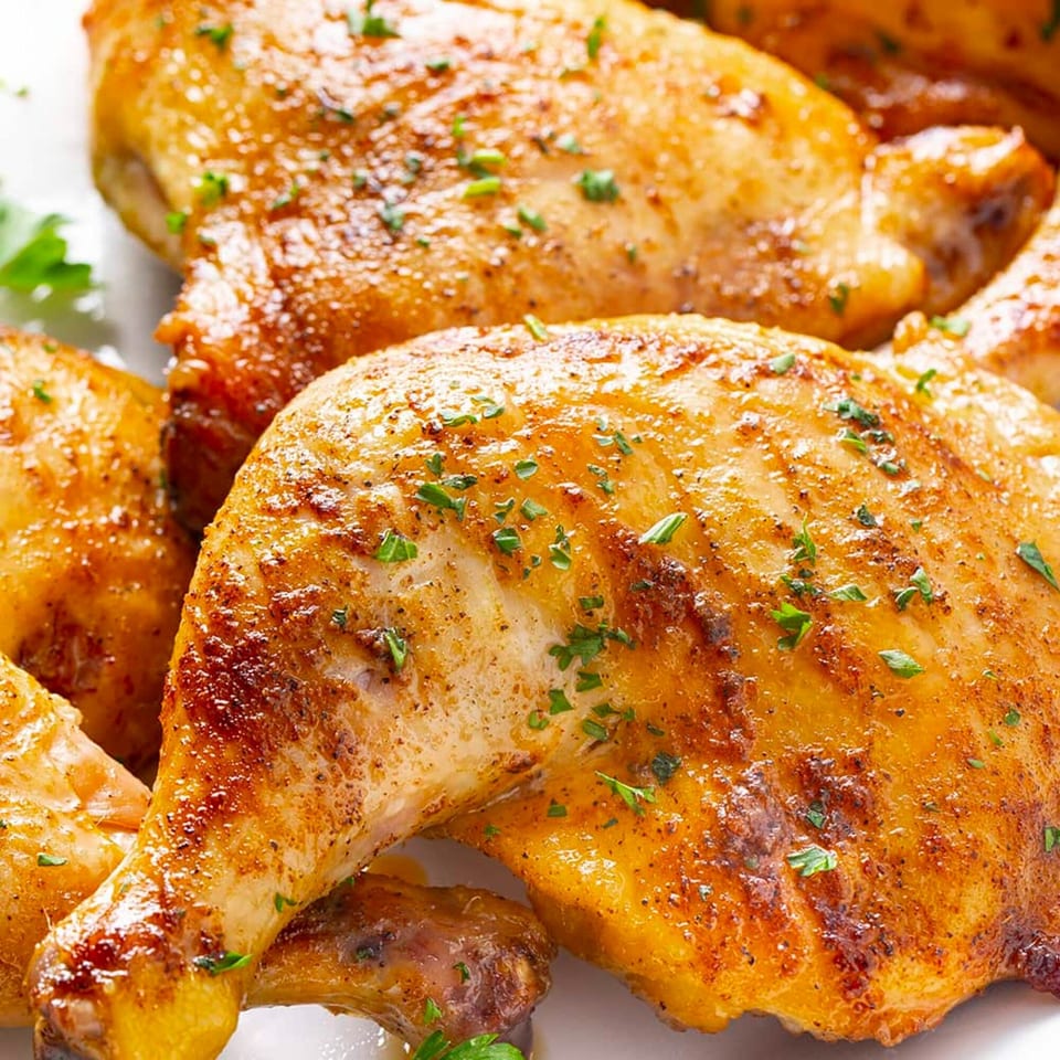 Golden-brown roasted chicken pieces, seasoned with herbs, on a white plate at Wings in Cuse.
